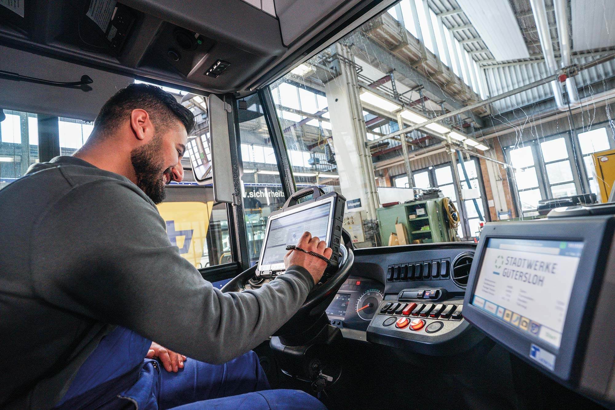 Der Busmechatroniker der Stadt Gütersloh arbeitet an der Bus-Technik und überprüft sorgfältig die Software, um sicherzustellen, dass alles reibungslos funktioniert.