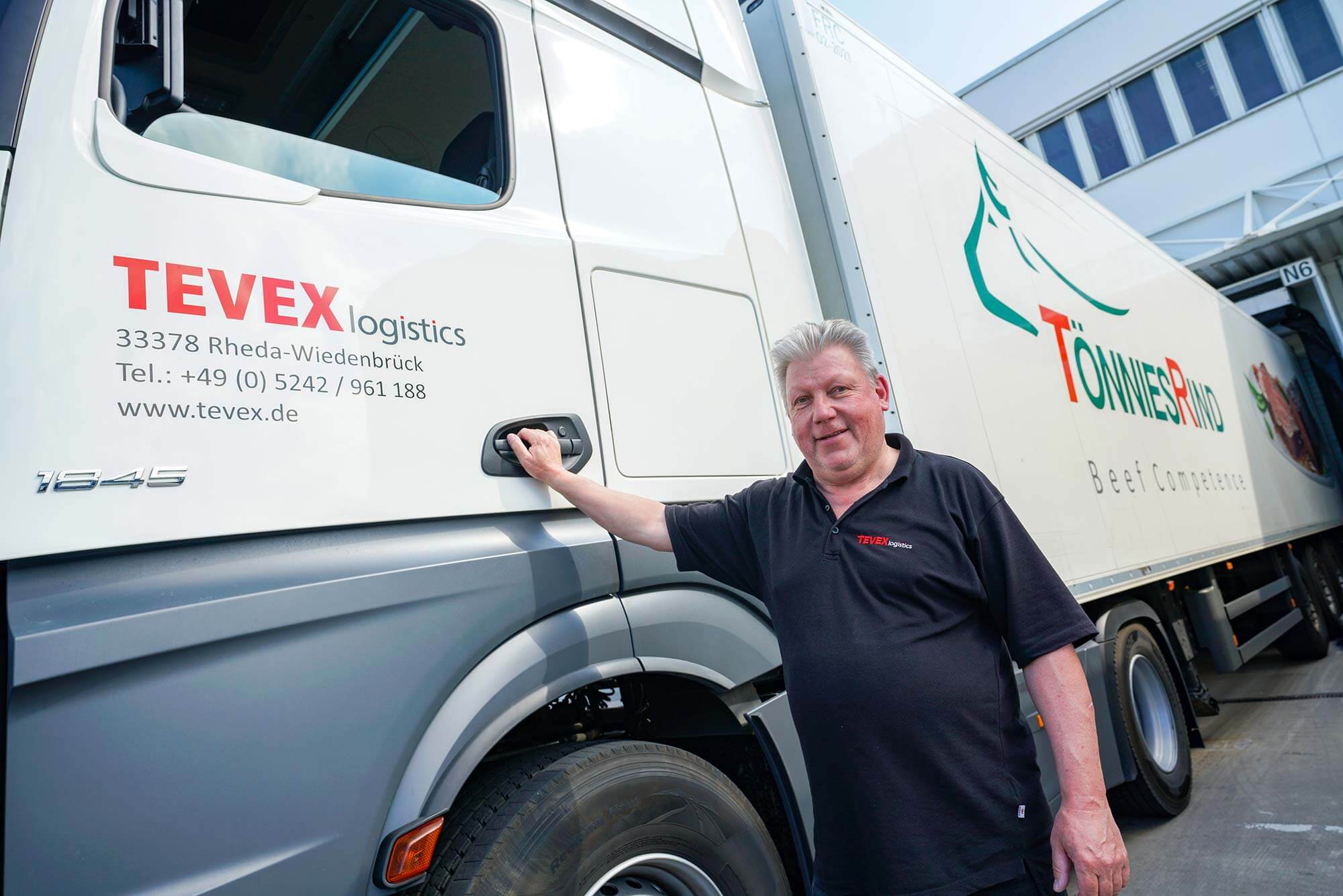 Ein stolzer Lastkraftwagenfahrer von Tönnies steht vor seinem Truck, der die Produkte im ganzen Land verteilt.